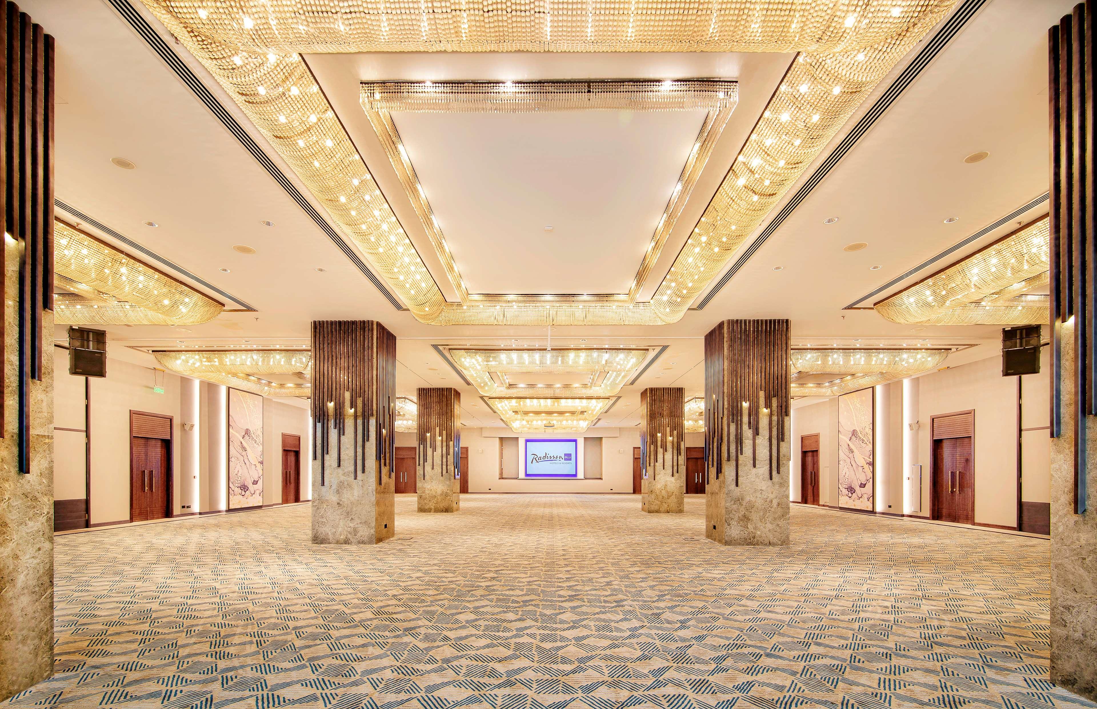 Radisson Blu Hotel & Resort, Abu Dhabi Corniche Esterno foto The photo depicts a spacious and elegantly designed interior hall, likely part of a conference or event venue. The ceiling features decorative lighting elements, providing a warm and luxurious ambiance. There are large pillars that frame the space, a