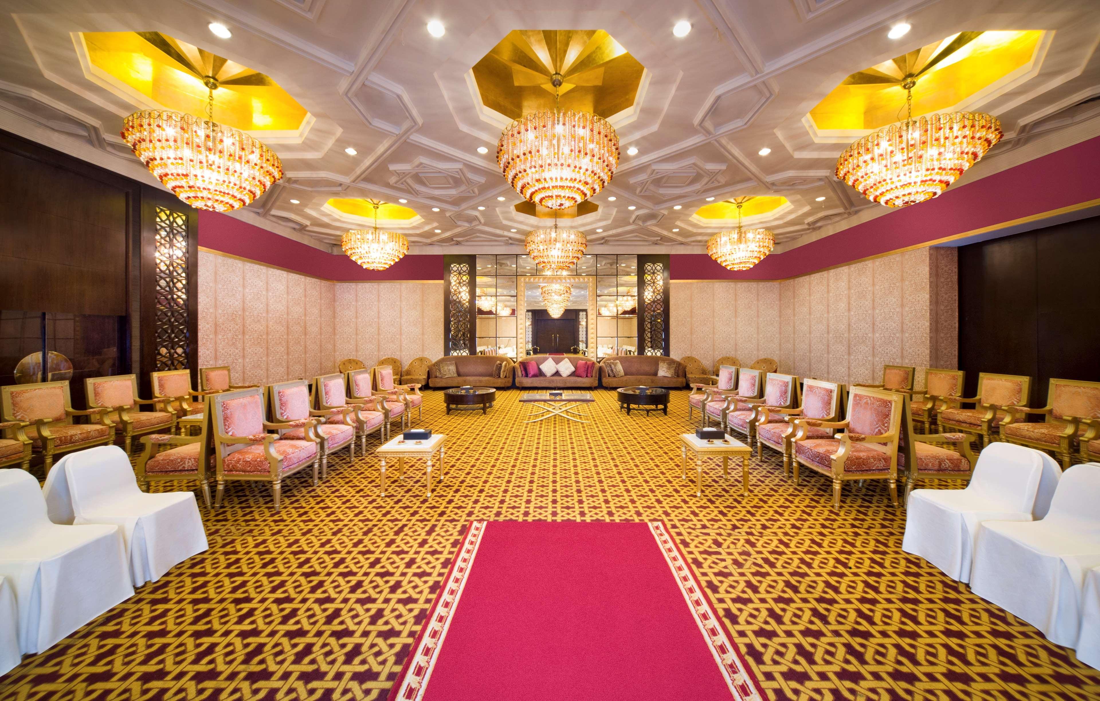 Radisson Blu Hotel & Resort, Abu Dhabi Corniche Esterno foto The photo shows an elegantly designed interior space, likely a banquet or conference room. The room features ornate chandeliers with golden accents hanging from the ceiling, providing ample lighting. The walls are decorated with a subtle pattern, and