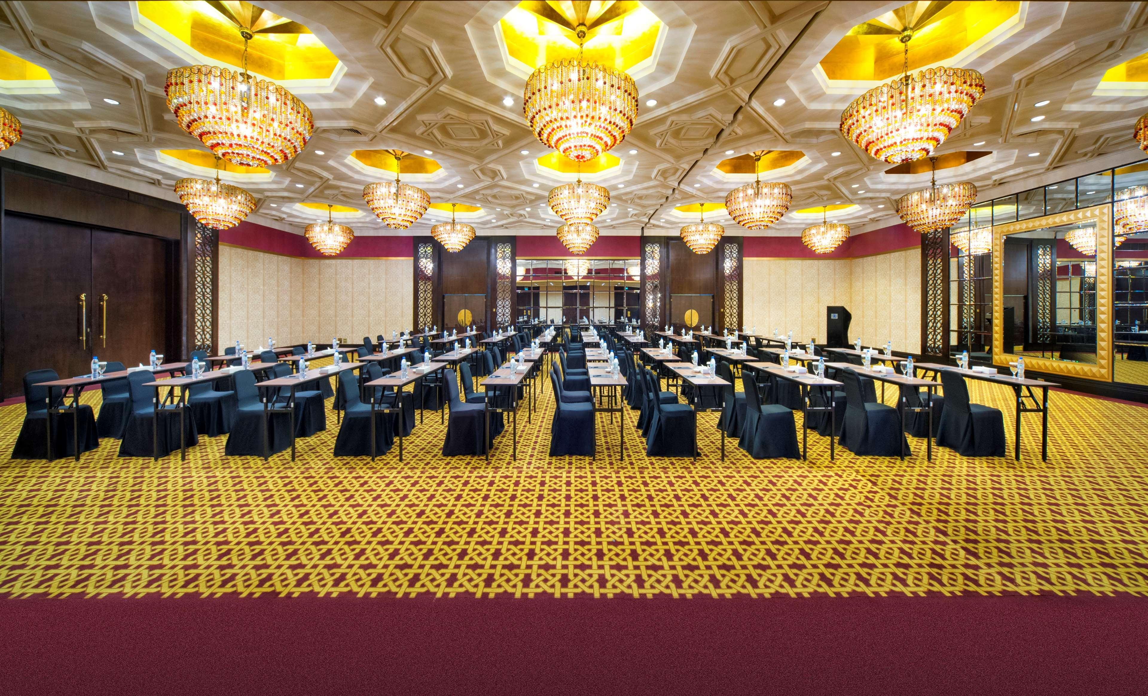 Radisson Blu Hotel & Resort, Abu Dhabi Corniche Esterno foto The image displays a banquet or conference hall with a luxurious interior. The room features a lavish ceiling adorned with intricate designs and multiple large chandeliers that provide bright lighting. There are long tables arranged in rows, each cov