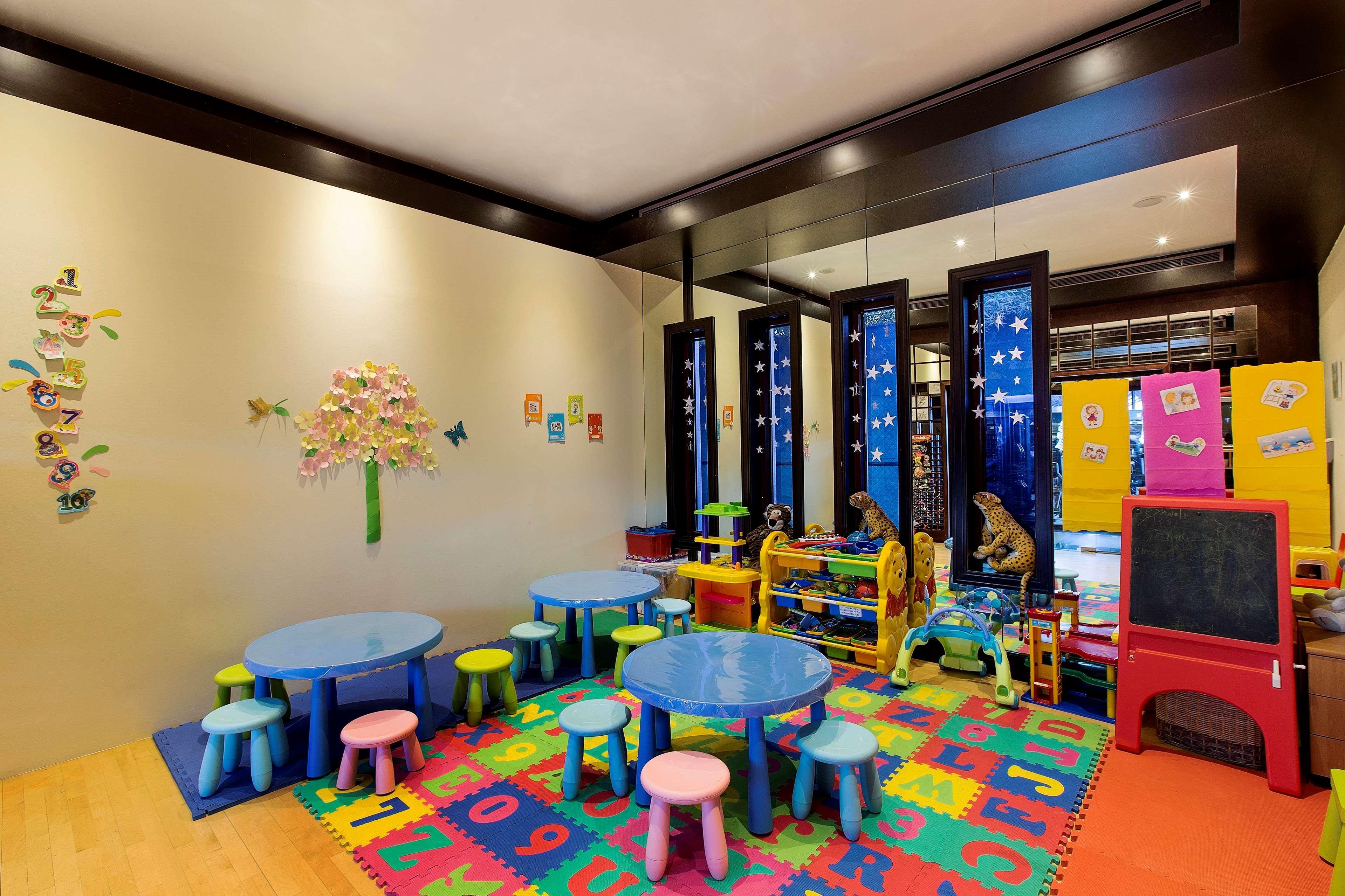 Radisson Blu Hotel & Resort, Abu Dhabi Corniche Esterno foto The photo shows a colorful and playful interior, likely a children's playroom or classroom. There are small blue tables surrounded by brightly colored stools in various pastel shades. The floor is covered with a multi-colored mat featuring letters an