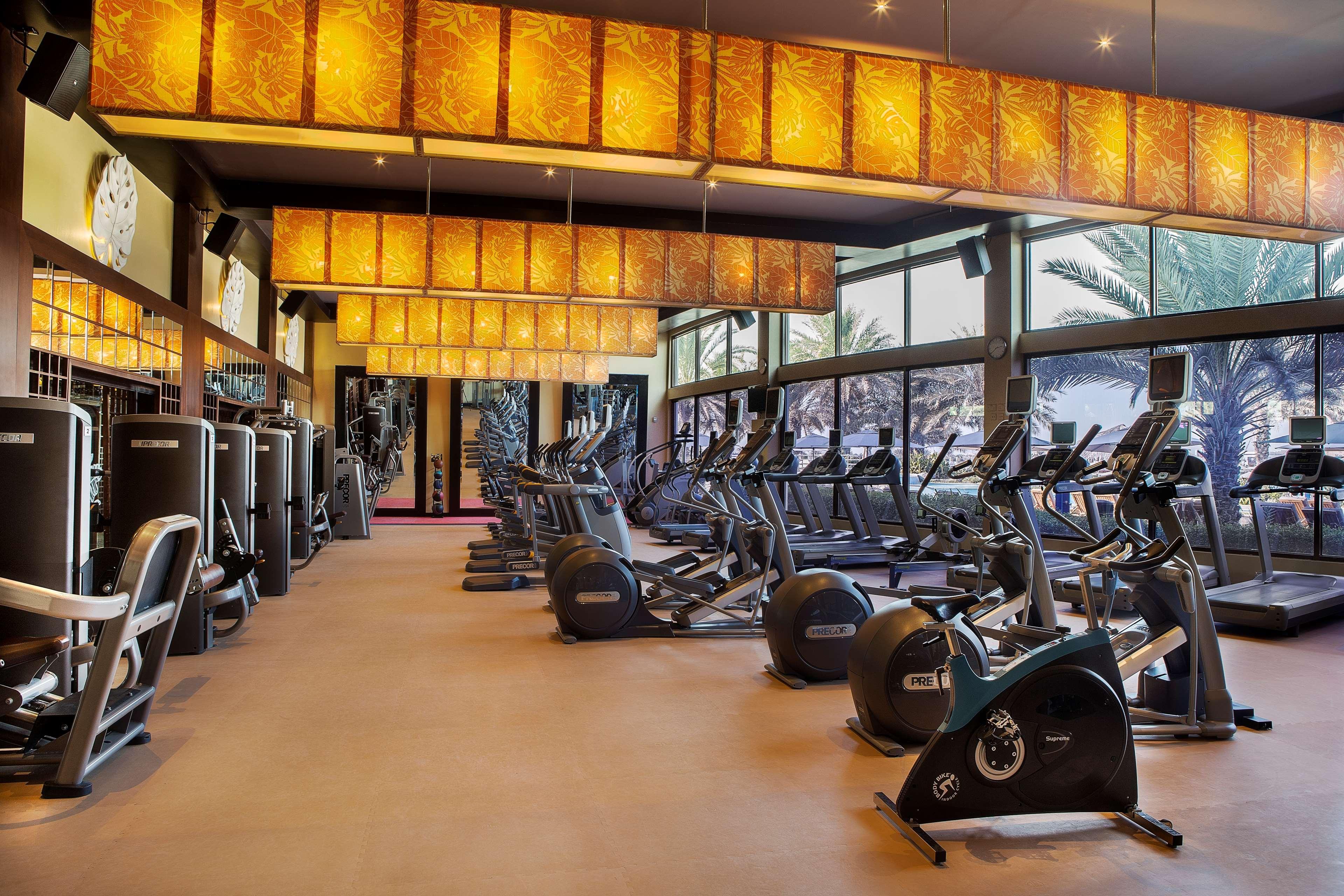 Radisson Blu Hotel & Resort, Abu Dhabi Corniche Esterno foto The photo shows a modern gym interior with various exercise equipment. The gym features multiple cardio machines, such as treadmills and stationary bikes, arranged neatly. Large windows allow natural light to enter the space, and the walls are decora
