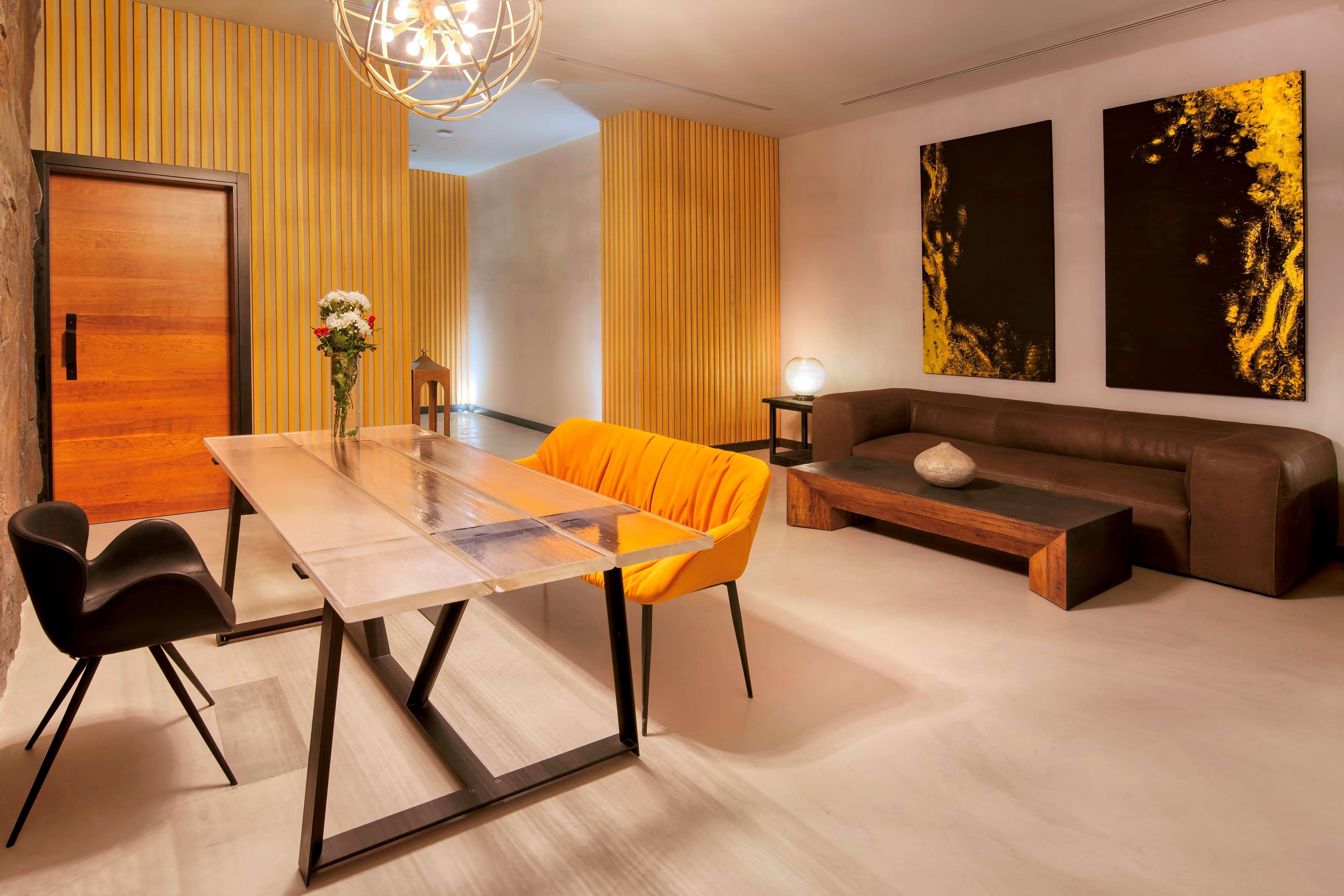 Radisson Blu Hotel & Resort, Abu Dhabi Corniche Esterno foto The photo shows a modern and stylish interior space. There is a minimalist dining or meeting table made of glass and metal, surrounded by black chairs. One of the chairs is bright orange, adding a pop of color to the room. In the background, there is